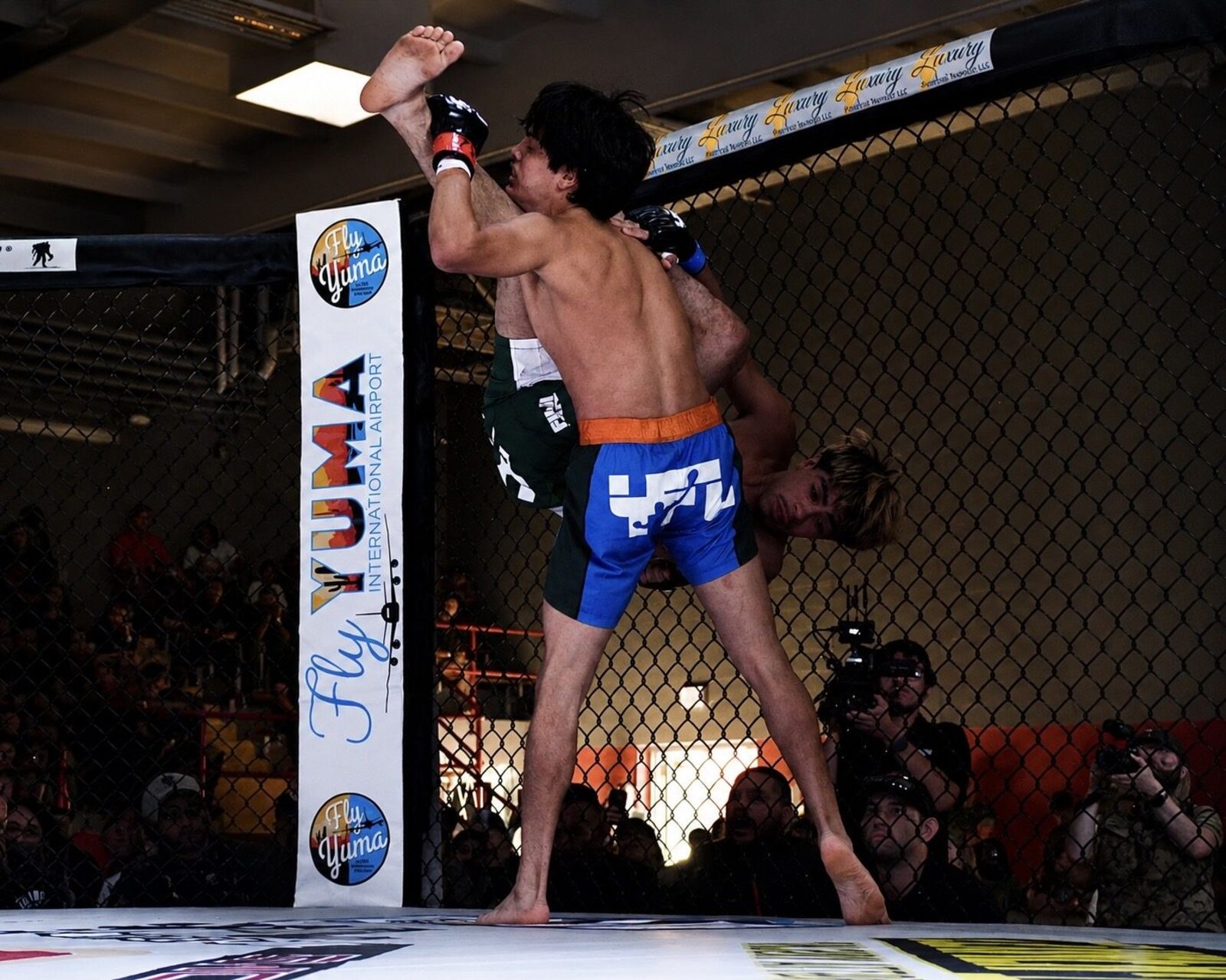 YFL fighter executing a flying knee with sponsor banners in background